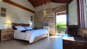 een slaapkamer met een bed en een stenen muur bij Casa Rural Sabariz in Sabariz