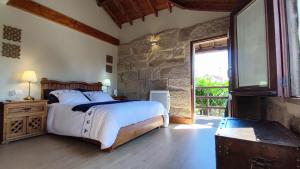 a bedroom with a bed and a stone wall at Casa de Turismo Rural Sabariz in Sabariz