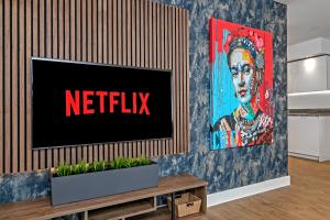 a television on a wall with the netflix sign on it at LUXURY AIRPORT SUITE, FREE Parking, FANTASTIC Location, Close To Airport, Train Station And Town Centre in Luton