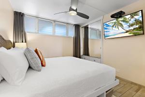 een slaapkamer met een wit bed en een flatscreen-tv bij Hale Ono Loa 117 in Kahana