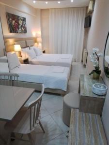 a hotel room with two beds and a table at LE MONDE Apartments in Nea Kallikrateia