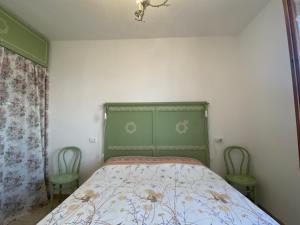 a bedroom with a bed with a green headboard and two chairs at Ca' Nostra in Ventimiglia +11 photos