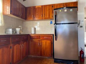 a stainless steel refrigerator in a kitchen with wooden cabinets at Elgords Vacations & Rentals in Christ Church