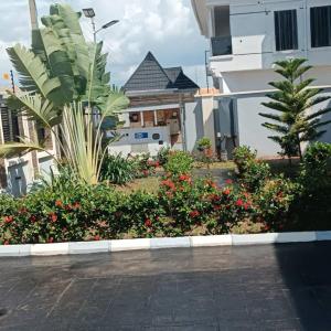 um jardim com flores e plantas em frente a um edifício em Prince's - Villa - Minimum of 3 nights booking em Akure