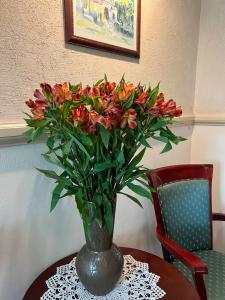 wazon kwiatów siedzący na stole w obiekcie Aparthotel Karmel w Krakowie
