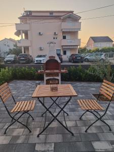 a picnic table and two chairs in front of a building at Apartman Mila in Biograd na Moru