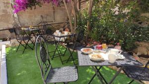 a table and chairs with food on it in a garden at L'Ajaccio B&B in La Maddalena