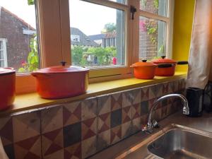 quatro potes sentados num balcão de cozinha numa janela em The Corner House em Kampen