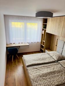 1 Schlafzimmer mit 2 Betten, einem Schreibtisch und einem Fenster in der Unterkunft Urban PORT apartment in Liptovský Mikuláš