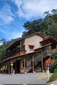 a house with a balcony and stairs on the side of it at Pousada Sítio das Pedras in Domingos Martins