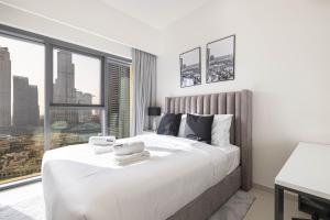 a bedroom with a large white bed with a large window at SmartStay at Burj Royale - Full Burj Khalifa View - Brand New Luxury Apartments in Dubai