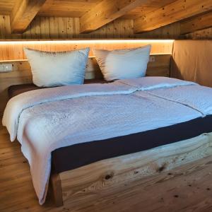 Bett mit weißer Bettwäsche und Kissen in einem Zimmer in der Unterkunft Ferienhaus Siebenschläfer in Rathen