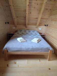 a bed in a wooden room with two towels on it at Brvnara Srna Zlatar in Nova Varoš