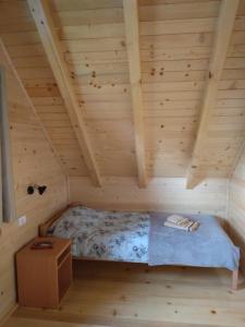 a bed in a wooden room in a log cabin at Brvnara Srna Zlatar in Nova Varoš