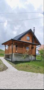 a large wooden house with a porch on a field at Brvnara Srna Zlatar in Nova Varoš