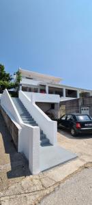 a white staircase in front of a building with a car at Apartments Lanterna in Sućuraj