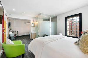 a bedroom with a large bed and a green chair at Inn 15 Brewery Loft Suites in Kingsville