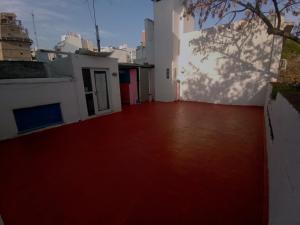Habitación con suelo rojo y edificio blanco en Refugio Porteño en Buenos Aires