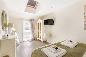a white bedroom with two towels on a bed at The Cowshed in Farmborough