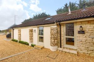 a stone house with a stone wall at The Cowshed in Farmborough