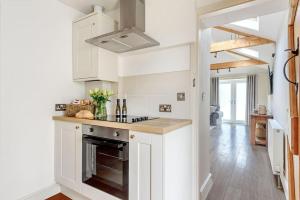 a kitchen with white cabinets and an oven at The Cowshed in Farmborough