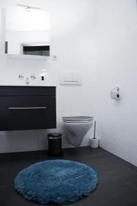 een badkamer met een blauw tapijt, een wastafel en een toilet bij Fresh apartment - 20th floor - Netflix - Center in Augsburg
