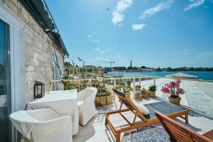 San Marco Luxury Rooms Umag في أوماغ: بلكونه ذات اثاث ابيض واطلالة على الماء