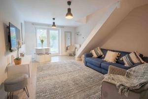 a living room with a blue couch and a staircase at Long-term stay for HS2 contractors & families in Marston Green