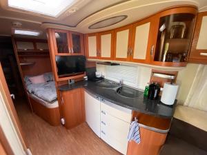 a kitchen in an rv with a sink and a tv at Luksusowy Kemping in Leśna