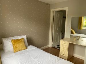 um quarto com uma cama, uma secretária e um espelho em No 3 Aughrim Holiday Village em Aughrim