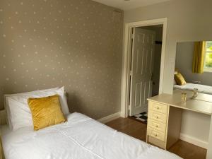 a bedroom with a bed and a desk and a mirror at No 3 Aughrim Holiday Village in Aughrim