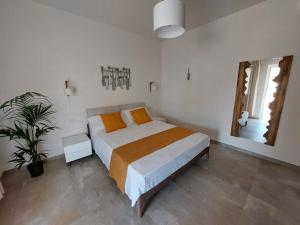 ランペドゥーザにあるLe Barche Volantiのベッドルーム1室(オレンジ色の枕と植物付)