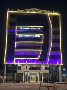 un grande edificio con luci viola di fronte di فندق ايلاف الشرقية 2 Elaf Eastern Hotel 2 a Sayhāt