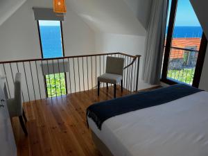 a bedroom with a bed and a chair in front of a window at CASAS DO LARANJO- Cottages & Infinity Pool in Gaula