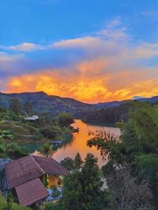 una vista de un río con una puesta de sol en el fondo en Descanso Bajo La Piedra Del Peñol, en Guatapé