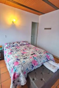 a bed with a floral comforter in a bedroom at Descanso Bajo La Piedra Del Peñol in Guatapé