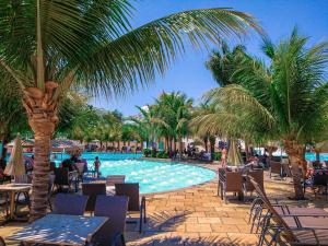 un complejo con una piscina con palmeras y mesas en L'ácqua diRoma VaciaTemporada, en Caldas Novas