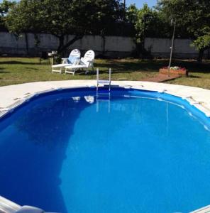 een groot blauw zwembad met twee stoelen in een tuin bij casa cumial in Ourense