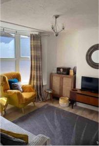 a living room with a yellow chair and a television at Balmoral Place, Ramsgate - 5 mins walk to Beach in Kent