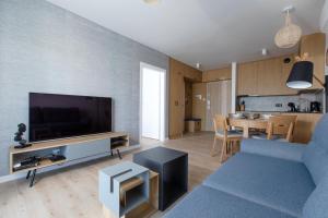 ein Wohnzimmer mit einer blauen Couch und einem Fernseher in der Unterkunft Apartament Szafirowy by Major Domus Club in Dziwnów