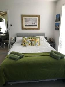um quarto com uma cama grande com lençóis e almofadas verdes em Log cabin rural retreat in beautiful countryside em Lapworth