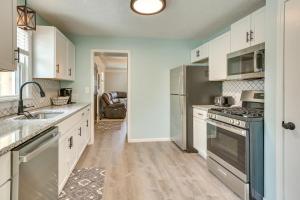 a kitchen with white cabinets and stainless steel appliances at Chippewa Lake Cottage with Fire Pit! in Chippewa Lake