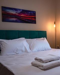a bed with white pillows and a painting on the wall at One Salonica Deluxe Apartment 3 in Thessaloniki
