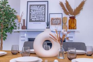 a dining room table with a large vase on it at Templar House - Sleeps 6, Special Weekly Monthly Stay Rates, Central Location with FREE Parking, FREE WiFi, Perfect for ALTON TOWERS & M6 in Stoke on Trent