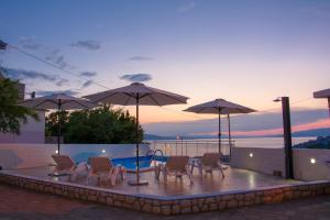 a group of chairs and umbrellas next to a pool at Apartman GROMILA in Senj