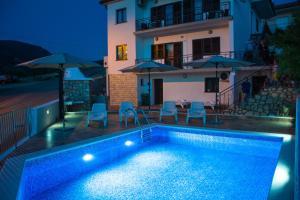 a swimming pool with chairs and umbrellas in front of a house at Apartman GROMILA in Senj