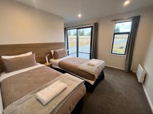 a hotel room with two beds and a window at Ahuru Mōwai in Lake Tekapo