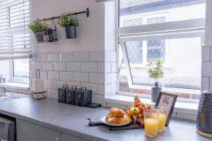 a kitchen counter with a plate of bread and orange juice at Templar House - Sleeps 6, Special Weekly Monthly Stay Rates, Central Location with FREE Parking, FREE WiFi, Perfect for ALTON TOWERS & M6 in Stoke on Trent