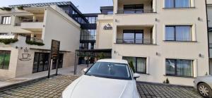 Un coche blanco aparcado delante de un edificio en Nota Apartman, en Vrnjačka Banja