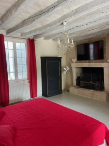 Schlafzimmer mit einem roten Bett und einem Kamin in der Unterkunft GITE ROMANTIQUE in Cléré-les-Pins